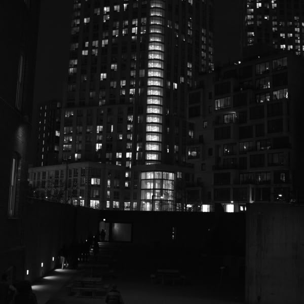 A city at night with a tall building and a bench.
