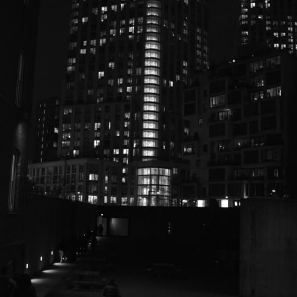 A city at night with a tall building and a bench.