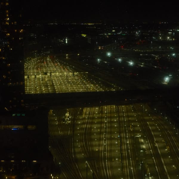 A city street at night with a bridge and a train.