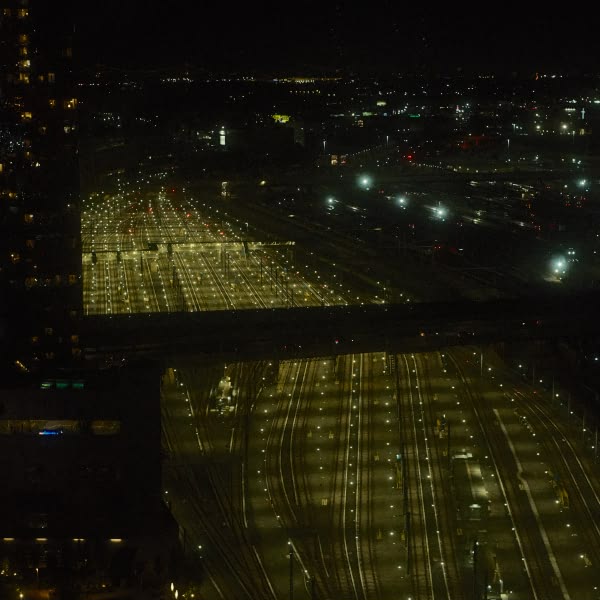 A city street at night with a bridge and a train.