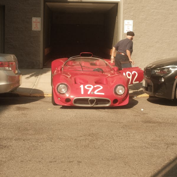 A red sports car is parked in front of a garage.