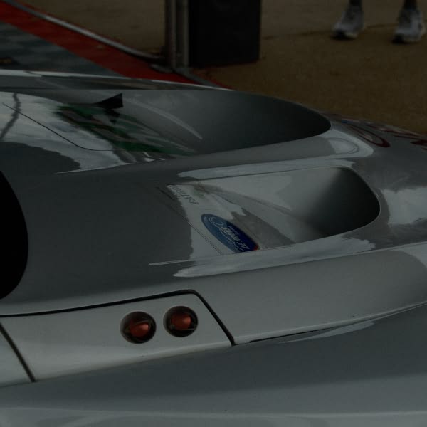 A silver car with a blue ford logo on the back.