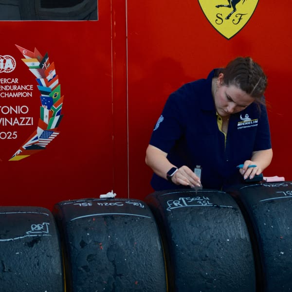 A woman wearing a blue shirt is writing on a tire.