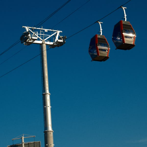 A blue sky with two red and white gondolas hanging from a pole.