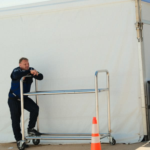 A man standing next to a metal cart.