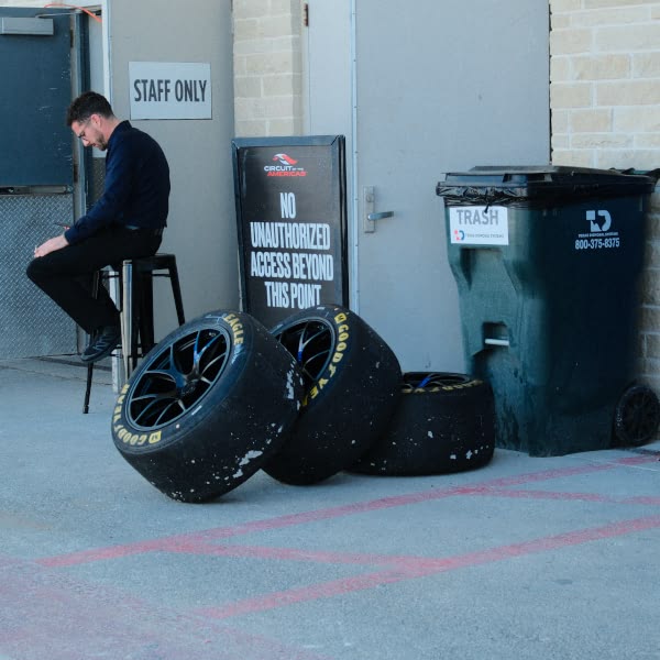 A man sitting on a stool next to a sign that says "staff only".