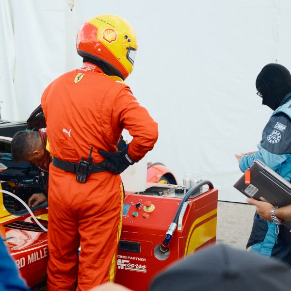 A man in a red suit is standing next to a red car.