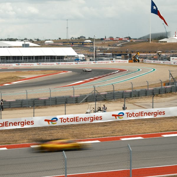 A yellow car is driving on a race track.