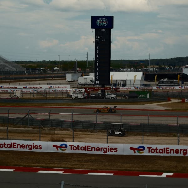 A race track with a yellow car driving on it.