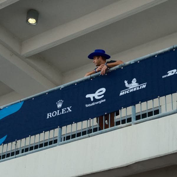A man wearing a blue hat is standing on a balcony.