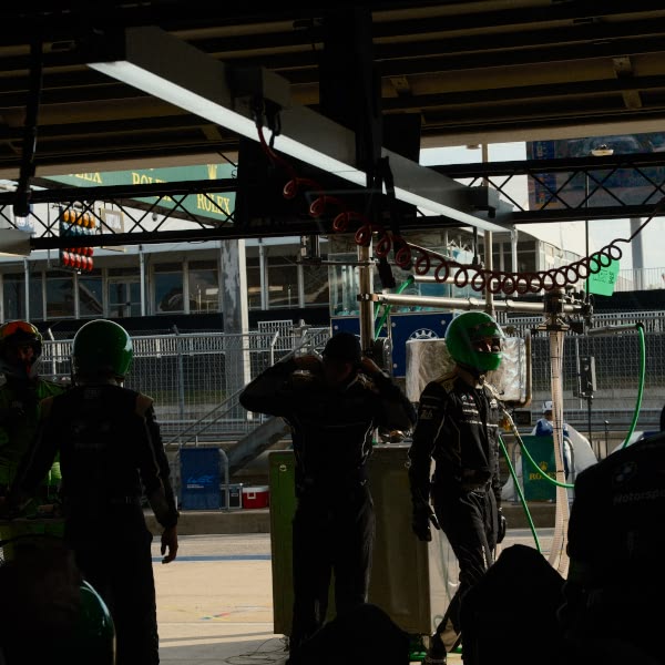 A group of men wearing green helmets standing in front of a building.
