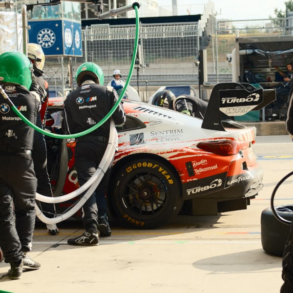A group of people working on a red race car.
