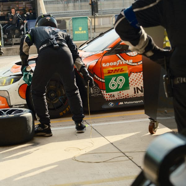 A man in a black suit is working on a race car.