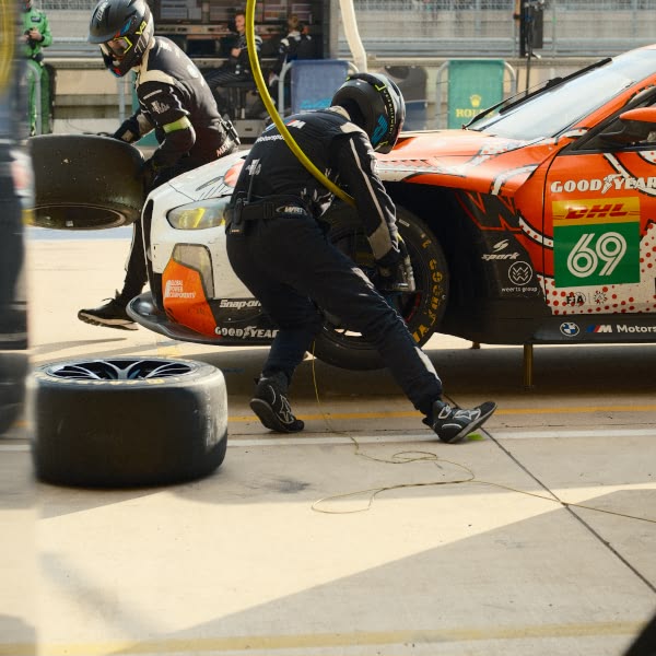 A man in a black helmet is working on a car.