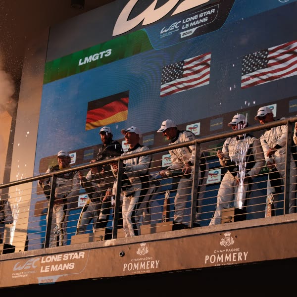 A group of men wearing white uniforms stand on a balcony.