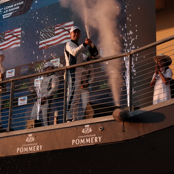 A man in a white suit is standing on a balcony.