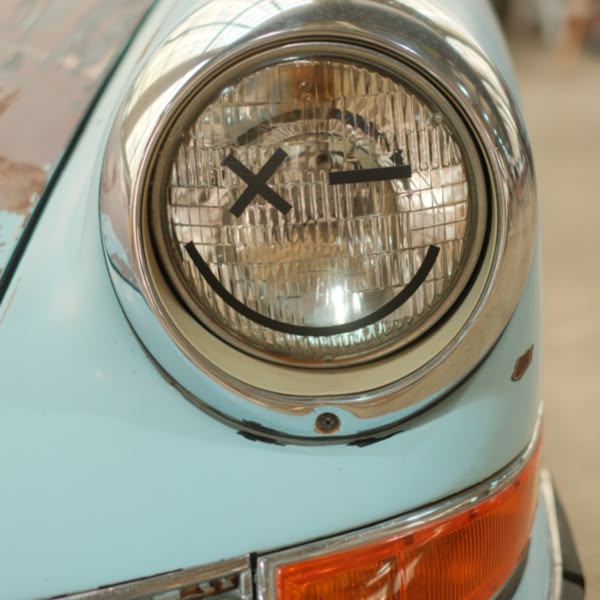 A blue car with a smiley face on the front light.