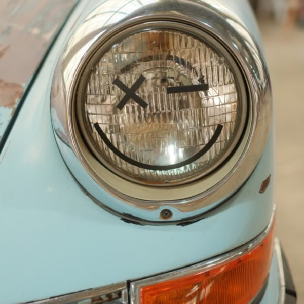 A blue car with a smiley face on the front light.