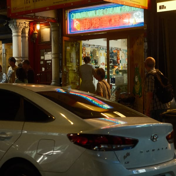 A white car is parked in front of a store.