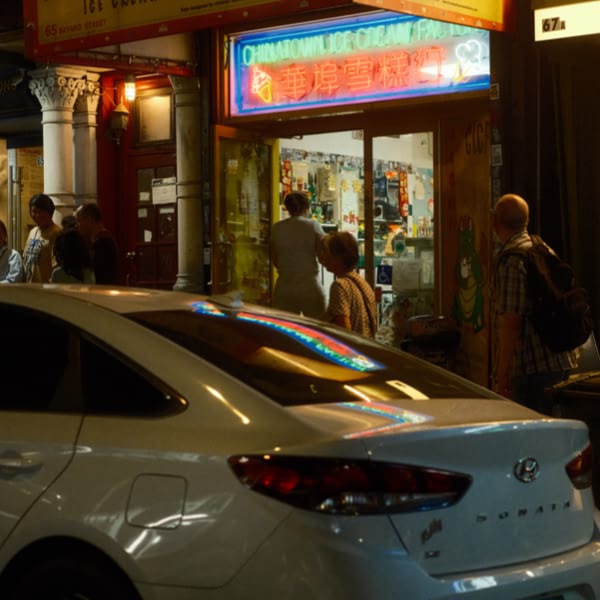 A white car is parked in front of a store.