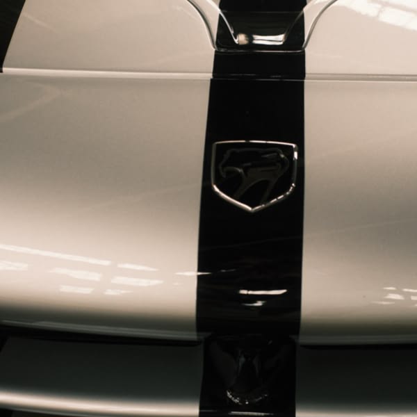 A white car with a black stripe on the hood.