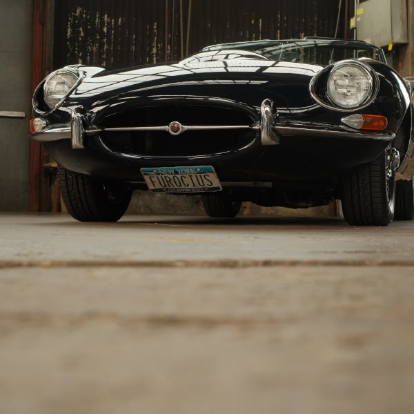 A blue sports car with the license plate "Furious" parked in a garage.
