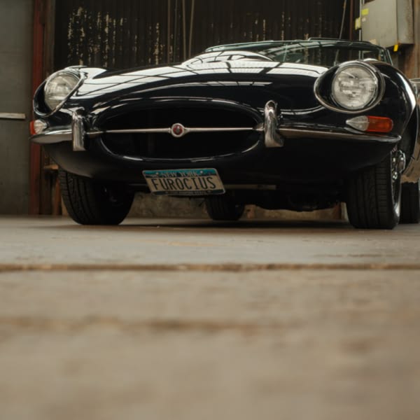 A blue sports car with the license plate "Furious" parked in a garage.