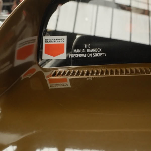 A brown car with a manual preservation society sticker.