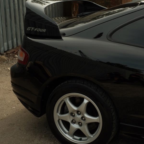 A black car with a spoiler on the back.