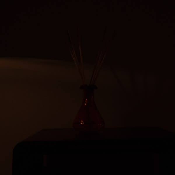 A red vase with a scent in it.