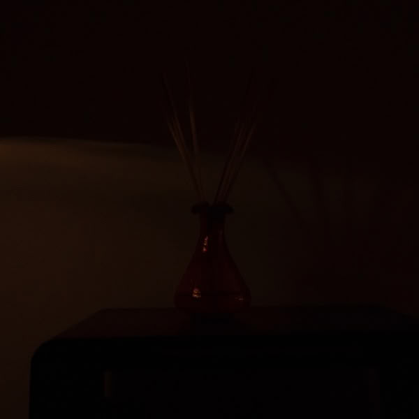 A red vase with a scent in it.