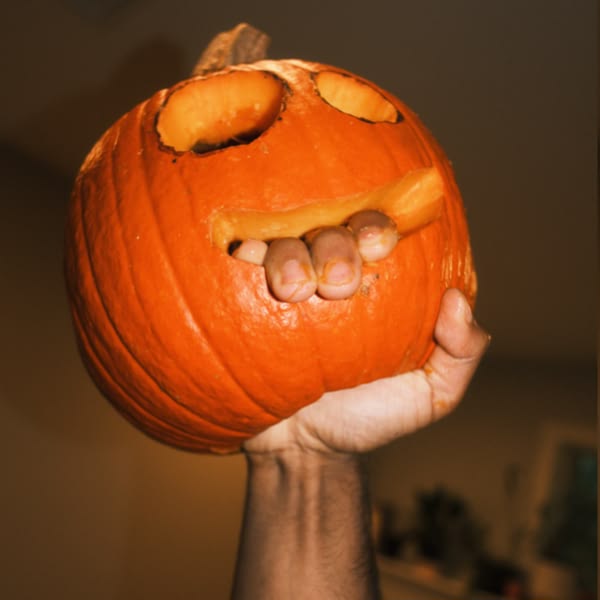 A hand holding a carved pumpkin.