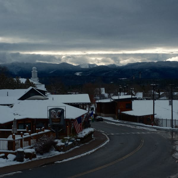 A snowy mountain road with a sign for a bar.