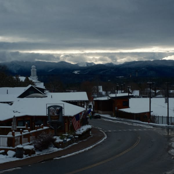 A snowy mountain road with a sign for a bar.