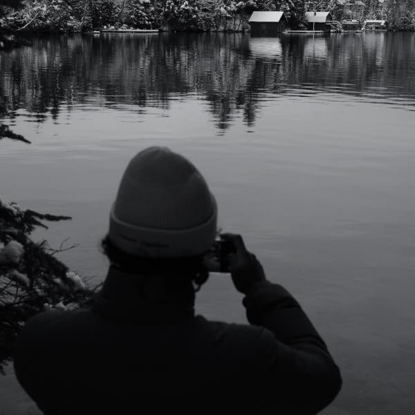 A man taking a picture of a lake.