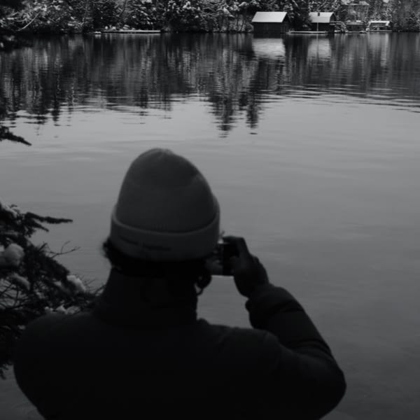A man taking a picture of a lake.
