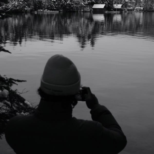 A man taking a picture of a lake.