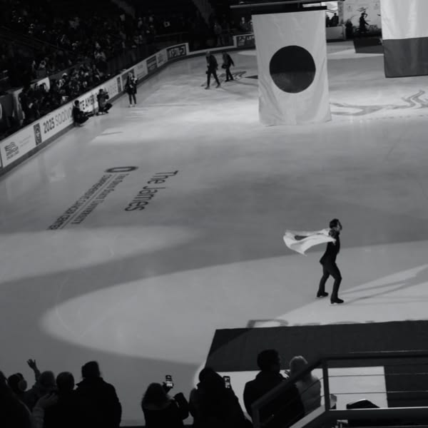 A man in a white cape skates on ice.