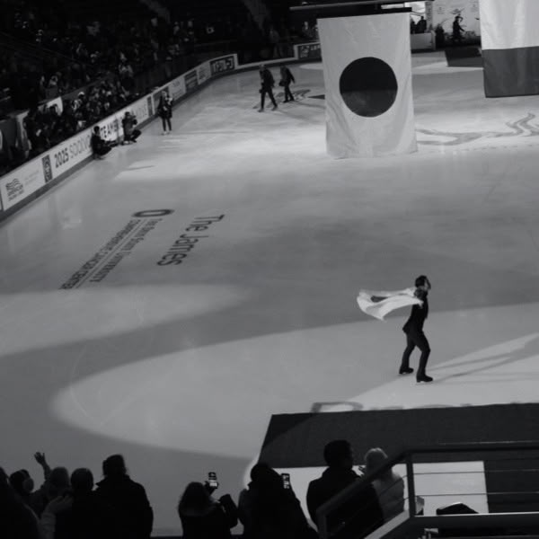A man in a white cape skates on ice.