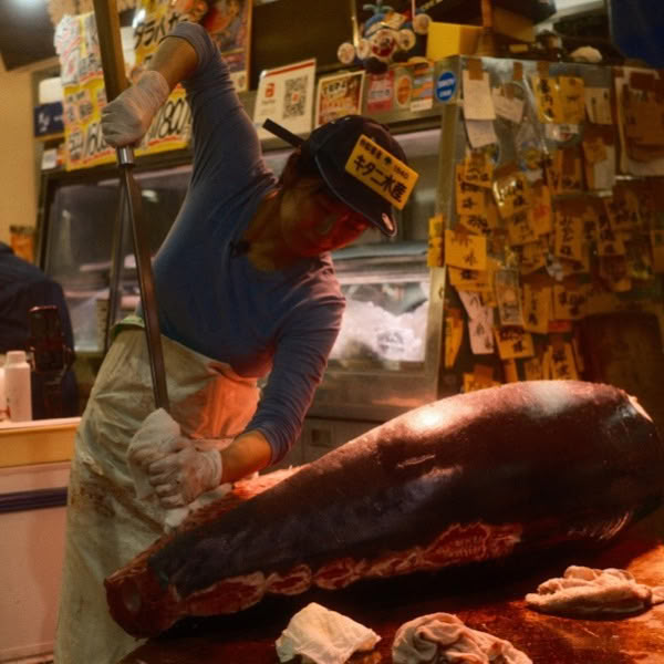 A woman cutting a large piece of meat.