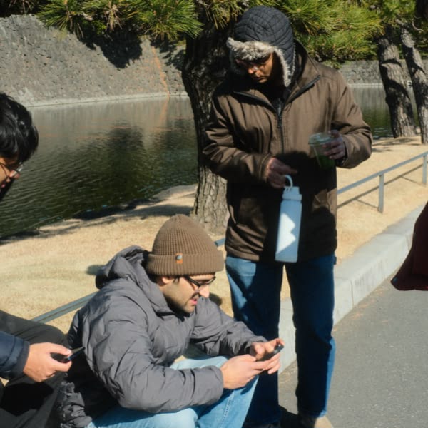 A man sitting on the ground looking at his cell phone.