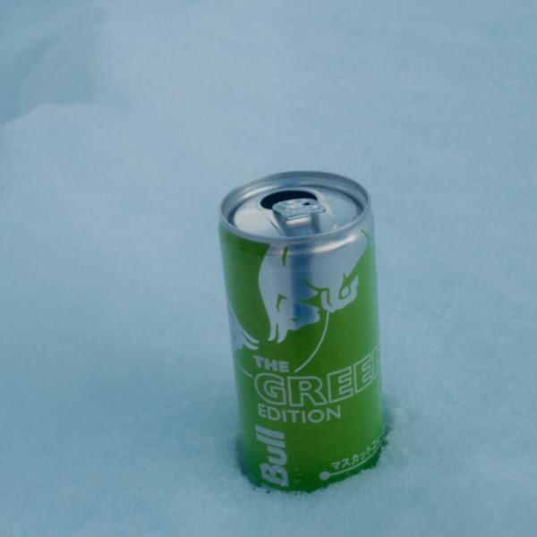 A green can of Bull is sitting in the snow.