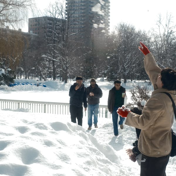 A person in a brown jacket is pointing at the snow.