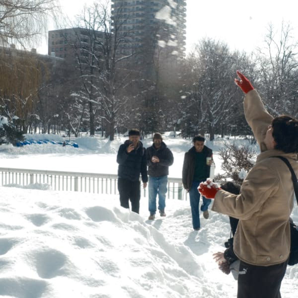 A person in a brown jacket is pointing at the snow.