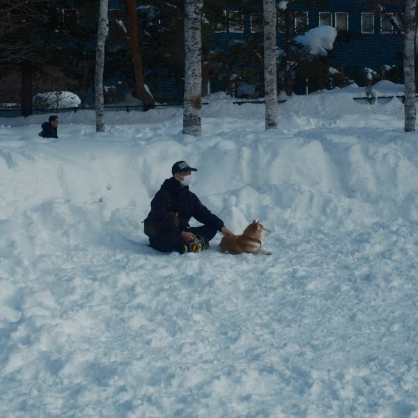 A man sitting in the snow with a dog.