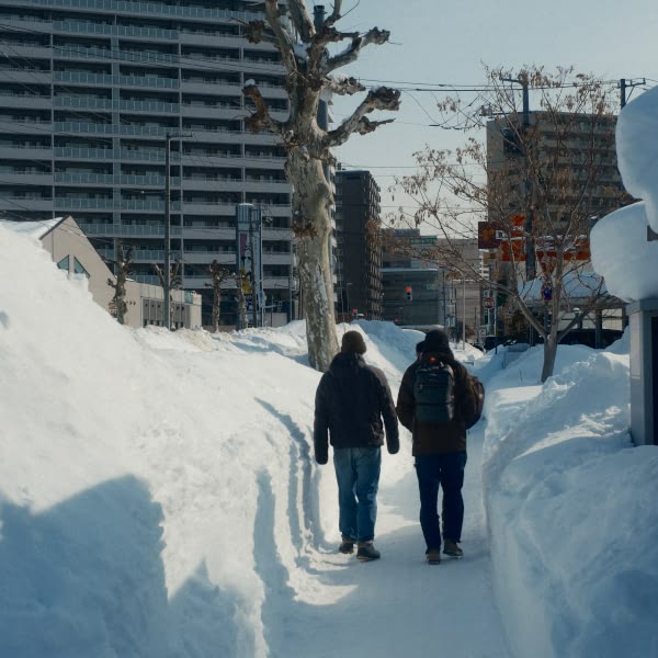 Two men walking on a snowy path.