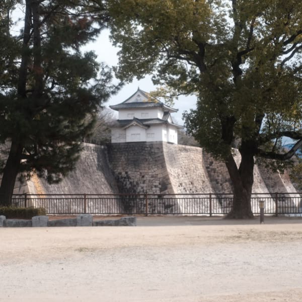 A stone wall with a small building on top.