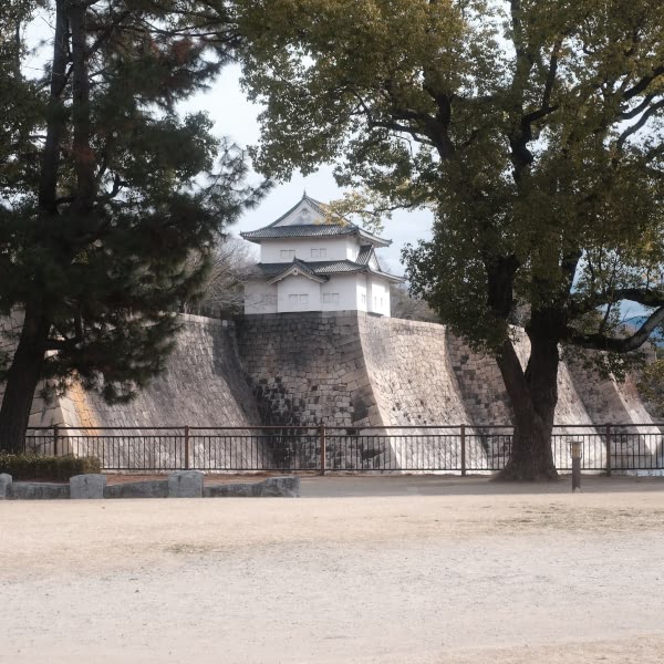 A stone wall with a small building on top.