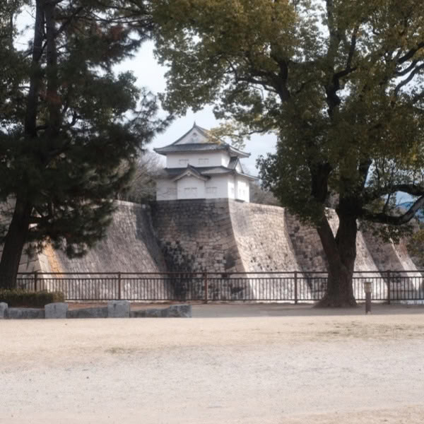 A stone wall with a small building on top.