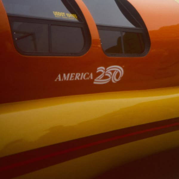 A red and yellow train with the words America 200 written on the side.